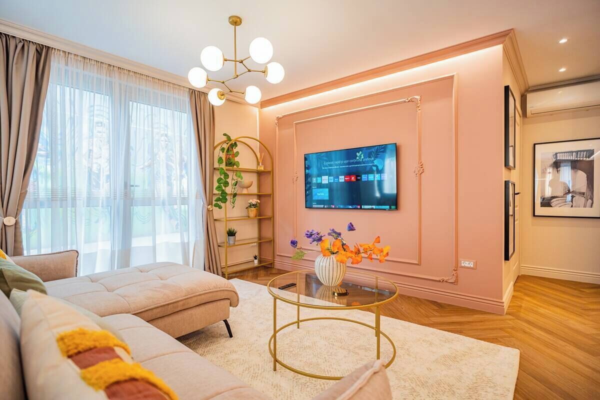 Ein modernes Wohnzimmer mit einem großen Flachbildfernseher an der Wand, einem bequemen Sofa, einem Glastisch und einer Zierpflanze.