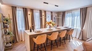A modern kitchen with a central island, bar stools, and a pendant light. - Pink Perfection -  1 Bedroom Designer Apartment in Bucharest (București)