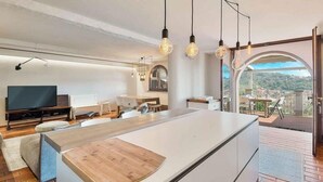 A modern kitchen with a central island, pendant lighting, and a view of the outdoors.