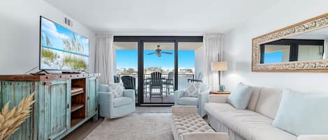 A living room with a TV, a sofa, a coffee table, and a view of the outside.