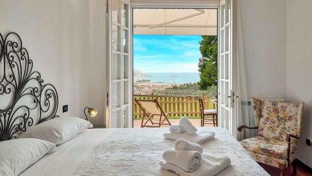 A bedroom with a bed, a chair, and a view of the sea. - Ai Colli 136, located in the renowned Zona Colli, is the perfect choice for you!This splendid property offers a large garden, ideal for relaxing in the sun, organizing outdoor dinners or simply enjoying the tranquility of the surrounding landscape.The ho (La Spezia)