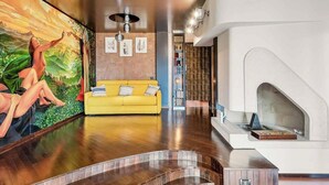 A modern interior with a yellow sofa, a mural, a fireplace, and a curved wooden floor. - Ai Colli 136, located in the renowned Zona Colli, is the perfect choice for you!This splendid property offers a large garden, ideal for relaxing in the sun, organizing outdoor dinners or simply enjoying the tranquility of the surrounding landscape.The ho (La Spezia)