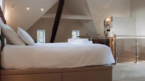 Un dormitorio con una cama grande, vigas de madera, una puerta de cristal y vistas al exterior.