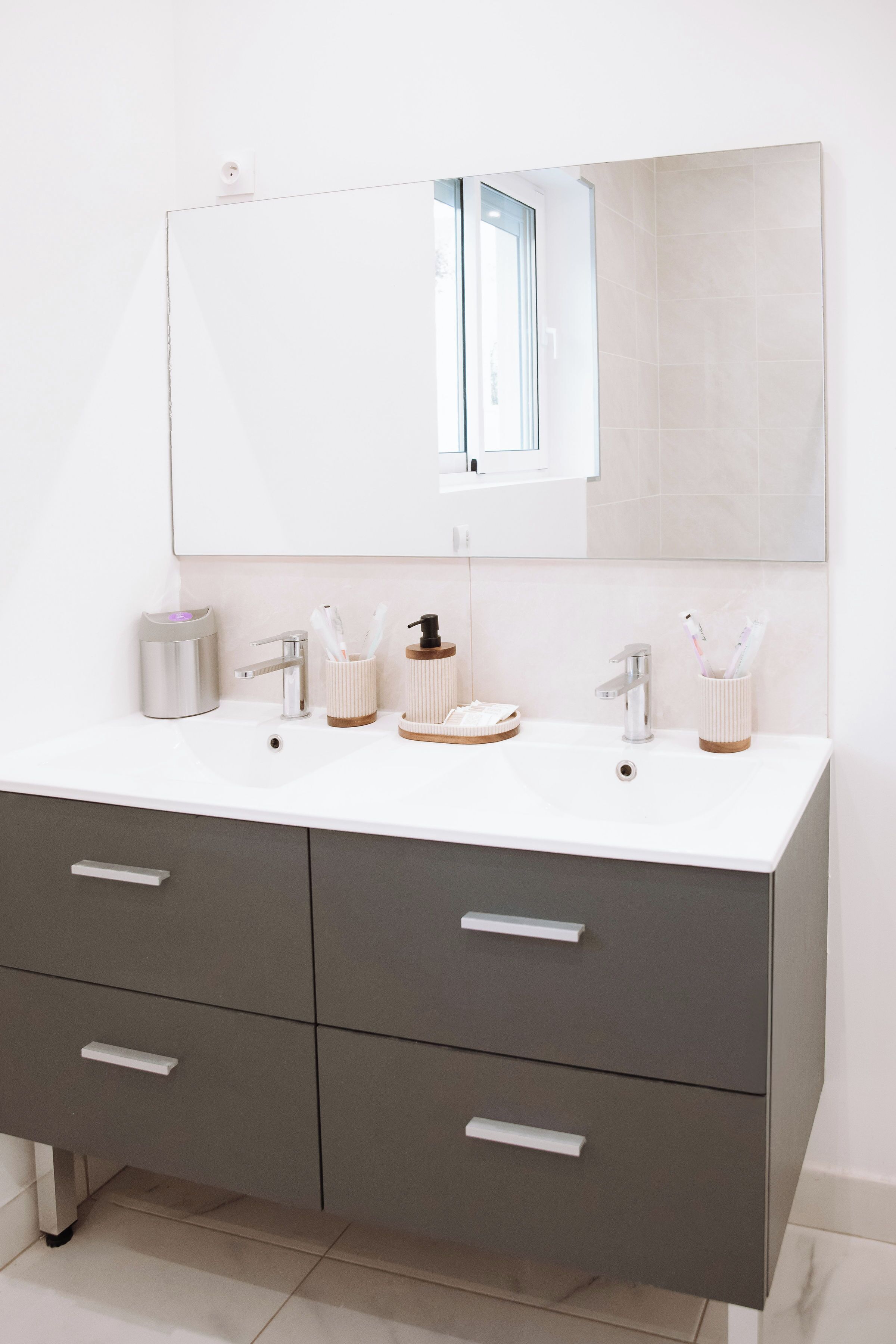 Une salle de bain moderne avec un meuble-lavabo blanc, deux vasques, un grand miroir et un meuble de rangement en bois.