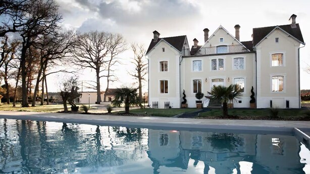 Una casa grande de dos pisos con piscina al frente.
