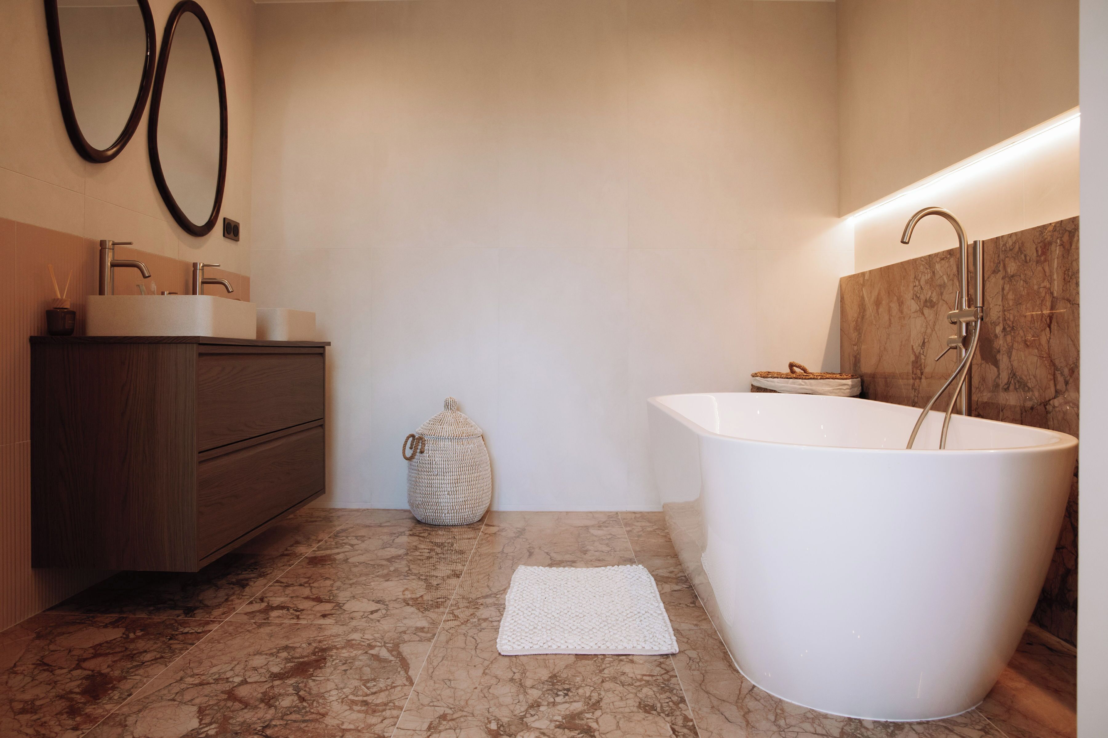 Une salle de bain moderne avec une baignoire sur pieds, un meuble-lavabo avec un miroir et un petit panier en osier.