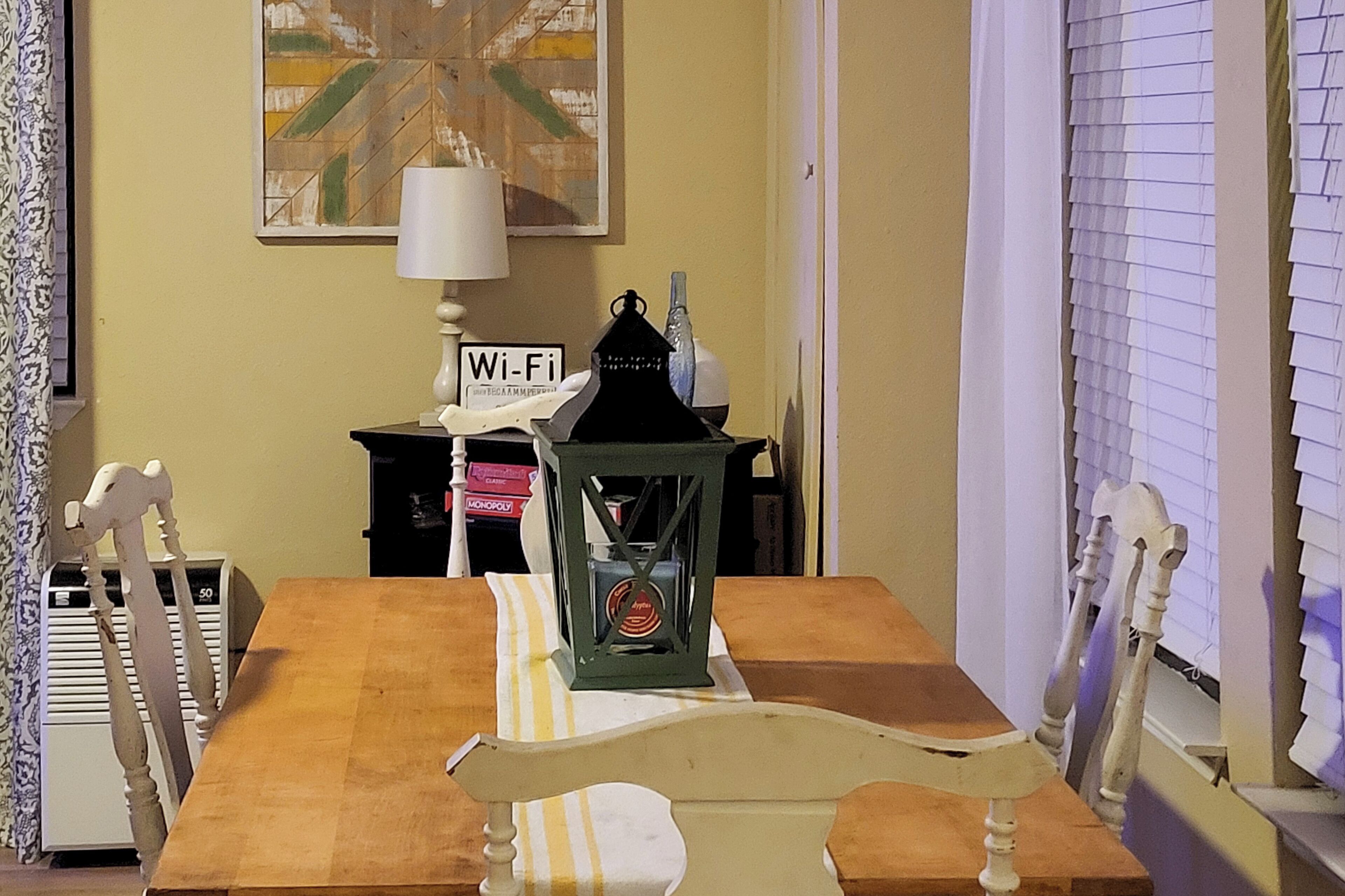 Een eethoek met een houten tafel, stoelen, een lamp en een Wi-Fi-bordje.