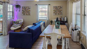 Un salon avec un canapé bleu, une table à manger en bois et un ventilateur de plafond.