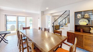 A spacious dining area with a large wooden table and chairs, a staircase leading to an upper level, and a view of the outdoors. - Escape the Heat! Lakefront Paradise in Mount Dora (Mount Dora)
