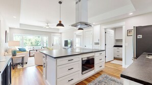 Una cucina moderna con mobili bianchi, un'isola grande e un forno integrato.