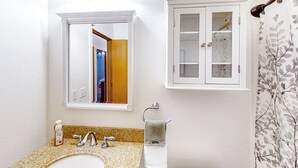 Uma casa de banho com lavatório, espelho e armário.