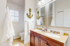 Un baño con dos lavamanos, un espejo grande y armarios de madera.
