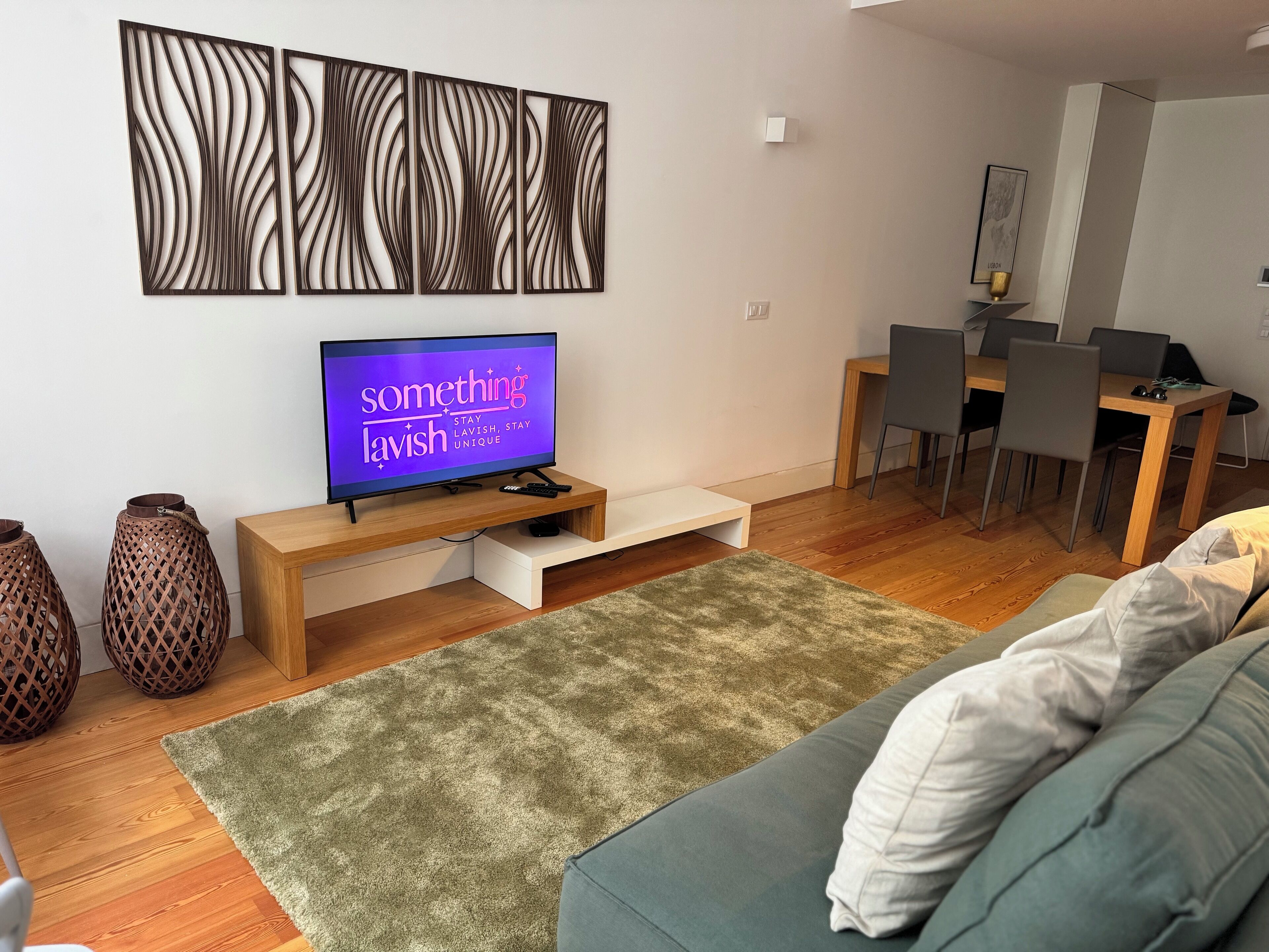 A modern living room with a flat-screen TV, wooden furniture, a green rug, and decorative vases.