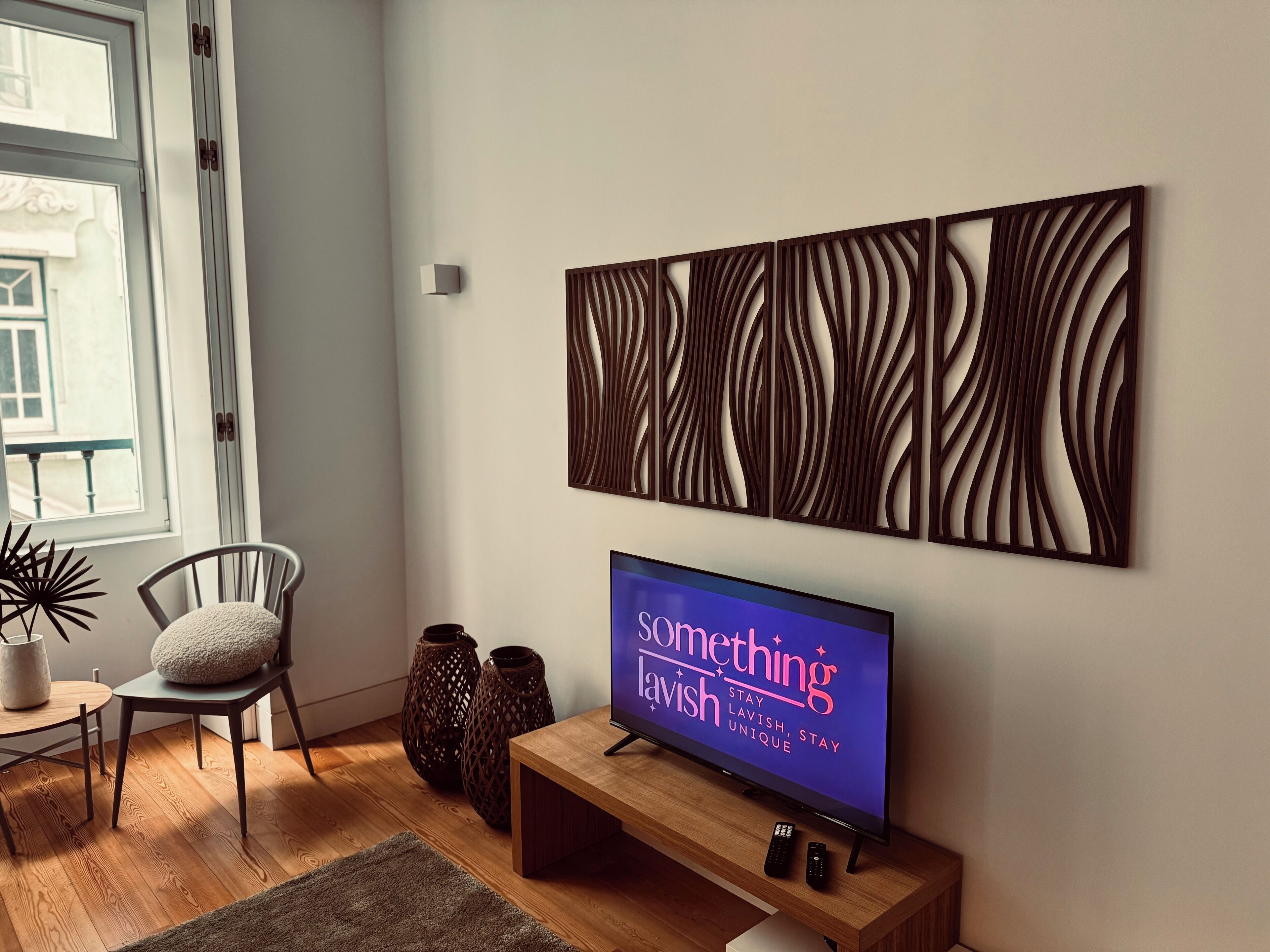 A modern living room with a flat-screen TV, wooden furniture, and decorative wall art.
