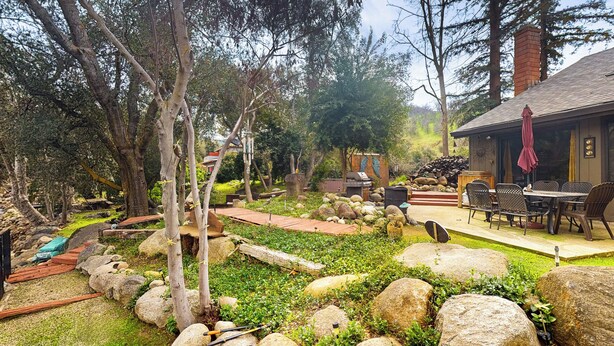 A rustic outdoor area with a wooden deck, stone pathway, and a dining area with outdoor furniture. - Yard & Patio: Quiet & Well-Stocked Riverside Home (Three Rivers)