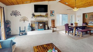 A spacious living room with a fireplace, wooden ceiling, and a dining area with a table and chairs. - Yard & Patio: Quiet & Well-Stocked Riverside Home (Three Rivers)