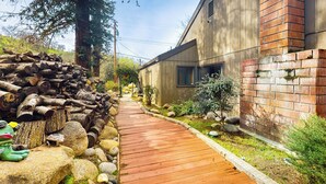 A wooden pathway leading to a modern building with a brick section and a wooden exterior. - Yard & Patio: Quiet & Well-Stocked Riverside Home (Three Rivers)