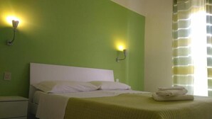 A hotel room with a bed, two wall-mounted lights, a nightstand, and a window with curtains. - Al Borgo Village (Pietra Ligure)