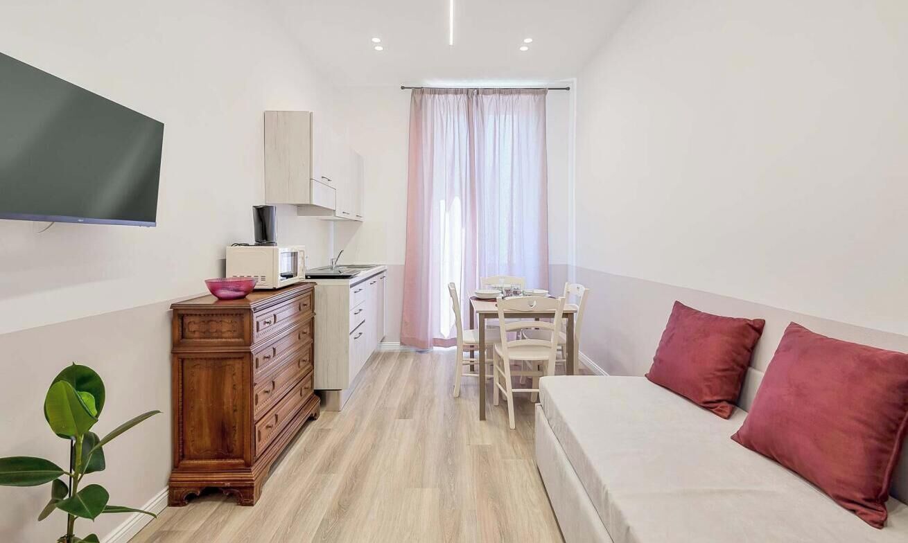 Camera d'albergo compatta con un letto, una scrivania, una sedia, un comò, un forno a microonde e una televisione.