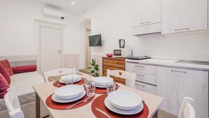Cocina moderna con armarios blancos, microondas y televisor sobre la encimera.