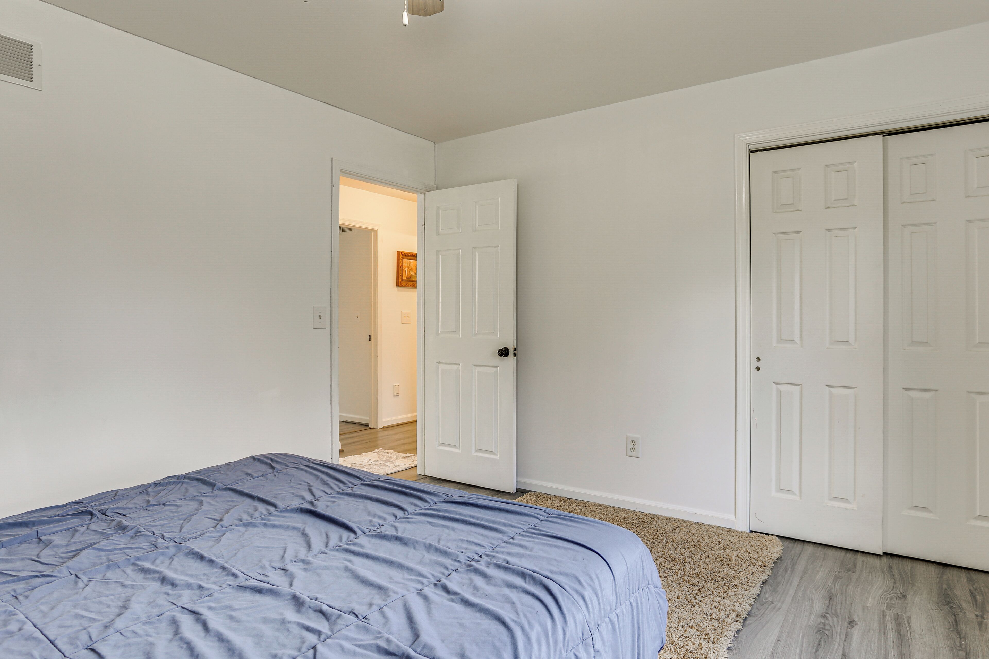 Ein Schlafzimmer mit einem Bett, einer Tür und einem Flur, der in einen weiteren Raum führt.