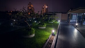A rooftop garden with potted plants and a pathway, overlooking a cityscape at night. - Modern 2 Bedroom Condo in Pratumnak (Muang Pattaya)