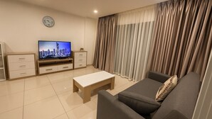 A modern living room with a flat-screen TV, a sofa, a coffee table, and a TV stand with drawers. - Modern 2 Bedroom Condo in Pratumnak (Muang Pattaya)