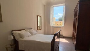 Une chambre à coucher avec un lit, une table de chevet, une fenêtre et une armoire.