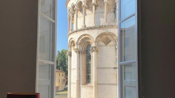 Une pièce dotée d’une fenêtre donnant sur un bâtiment historique orné d’arcades.