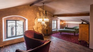 Una habitación con una silla roja, un sofá verde, un armario de madera, un piano de cola y un violonchelo grande.