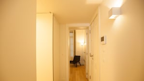A narrow hallway with wooden flooring, white walls, and a chair in the distance. - FLH Downtown Central Minimalist Apartment (Lisboa ciudad)