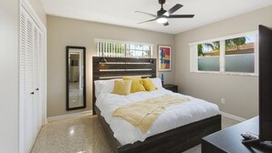 Ein Schlafzimmer mit einem Bett, Deckenventilator, Fenster und Tür.