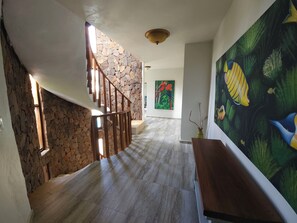 Eine Treppe mit Holzwertschrankungen führt zu einem Raum mit einer Steinwand und einem großen Wandbild von einem Fisch.