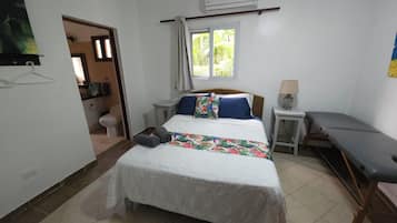Quarto com cama, mesas de cabeceira, janela e ar condicionado.