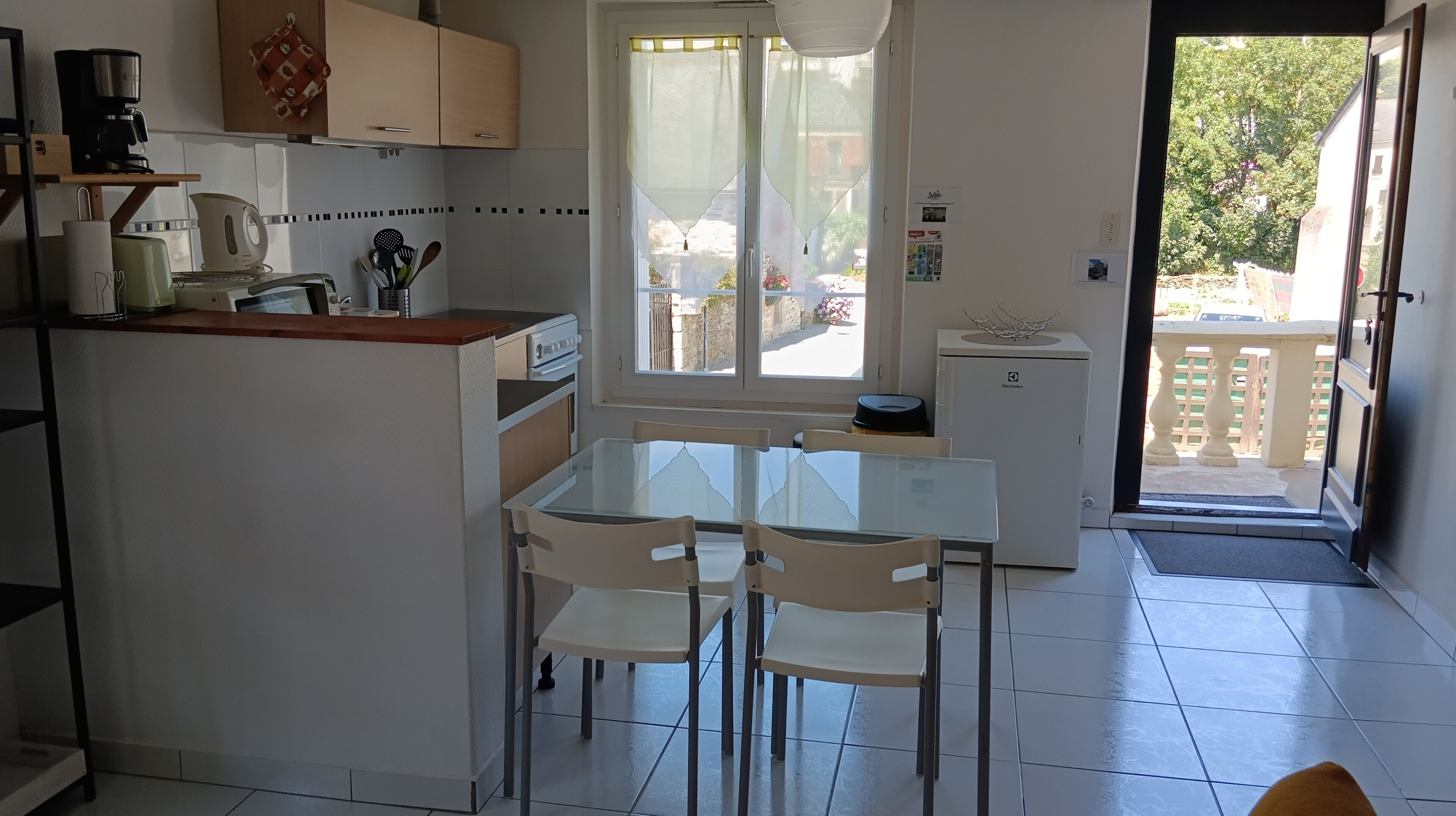 Una cuina compacta amb zona de menjador, que compta amb un frigorífic, cafetera i una petita illa amb un rentapeus.