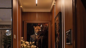 A hallway with wooden paneling, a fur rug, a leopard print artwork, and a vase of flowers. - One Bedroom Luxury apartment in Maitama, Abuja (Abuja)