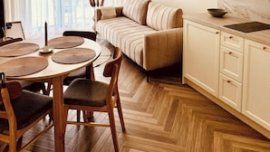 Una cucina moderna con pavimento a spina di pesce, un divano beige e un'area pranzo con un tavolo rotondo e sedie.