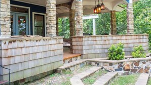 A covered porch with stone columns, a wooden bench, and a stone wall. - Creekside Haven With Dock Scenic Views (Hollywood)