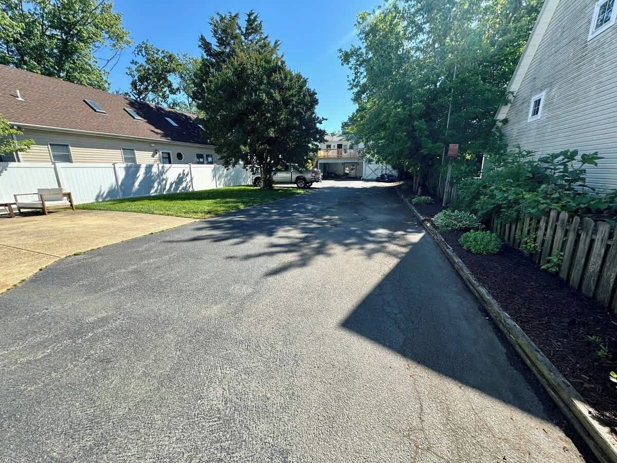 A residential street with houses on both sides, a driveway, and a lawn area.