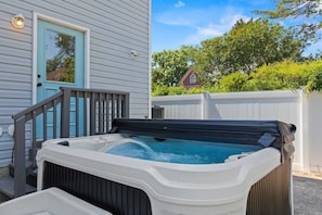 A hot tub outside a house with a wooden deck and a white fence. - Solomons Island 6BR Family Getaway (Solomons)