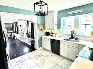 A kitchen with white cabinets, a black countertop, and a sign that reads "Solomons Island". - Solomons Island 6BR Family Getaway (Solomons)