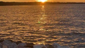 A sunset over a body of water with a rocky shoreline in the foreground.