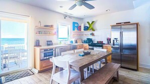 A modern kitchen with a wooden table and chairs, a stainless steel refrigerator, and a ceiling fan. - 4-bedroom Luxury Private Beach Getaway (Scotland)