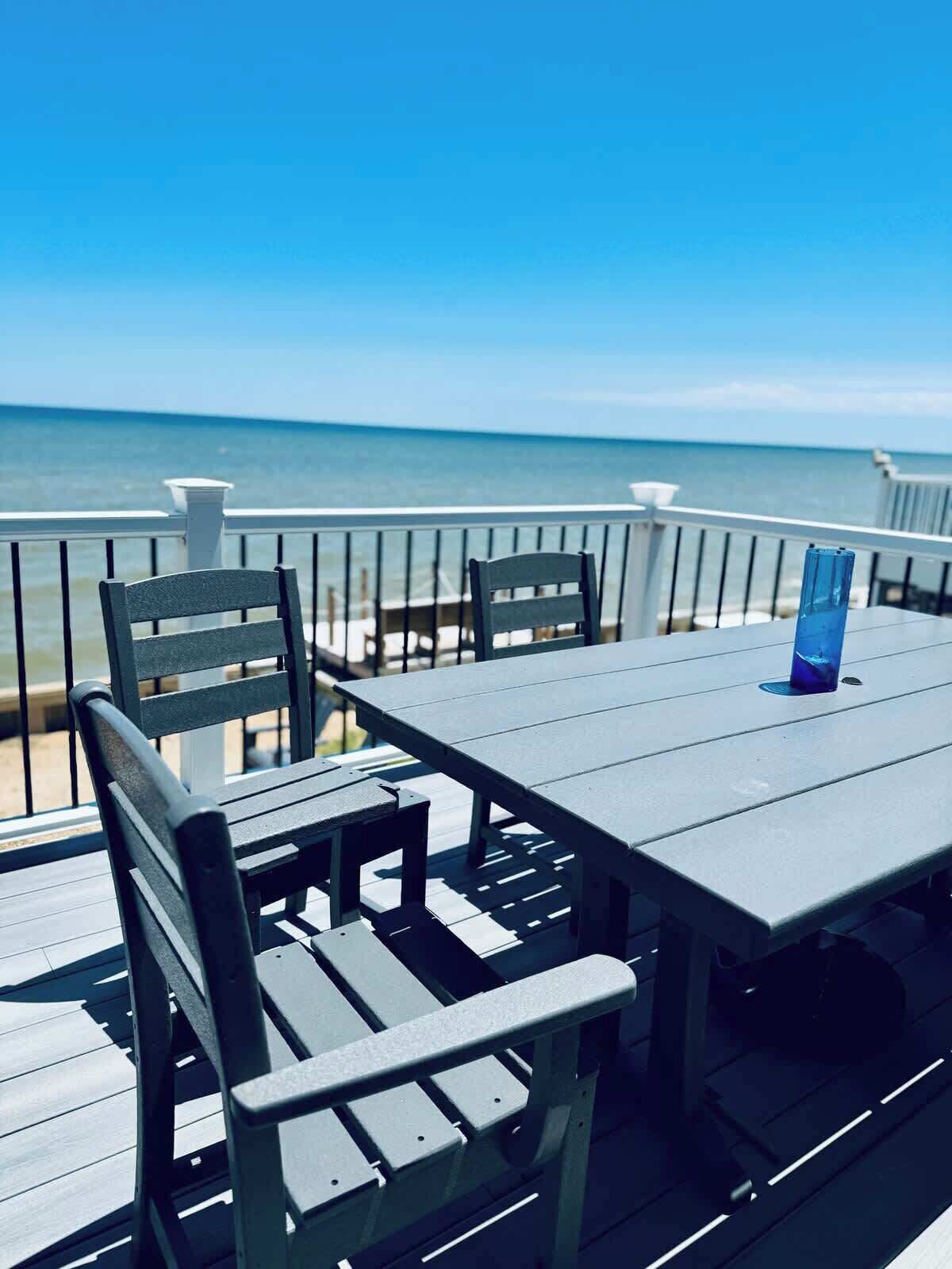 A deck with a table and chairs overlooking the ocean.