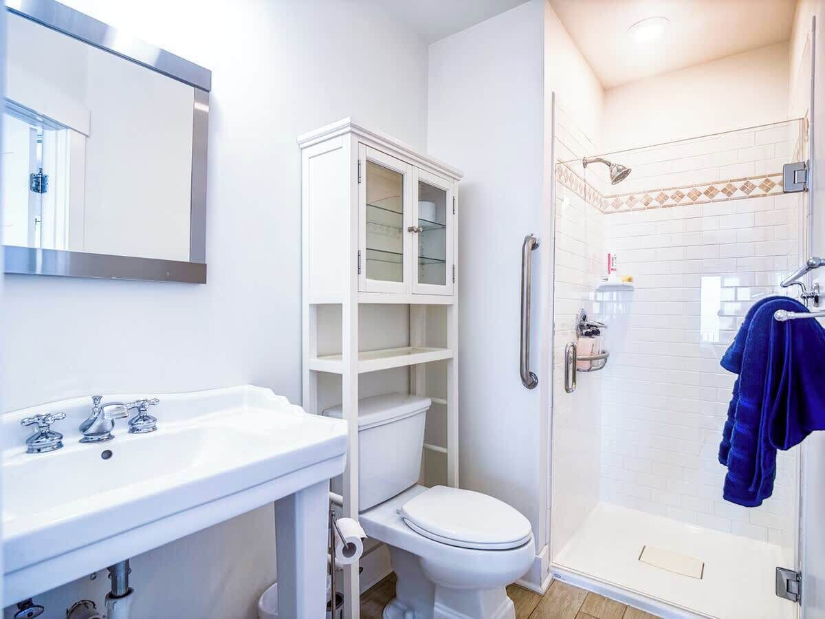 A bathroom with a white sink, toilet, and glass-enclosed shower.