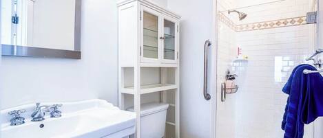 A bathroom with a white sink, toilet, and glass-enclosed shower.