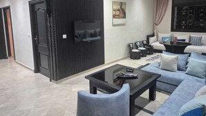 Uma sala de estar moderna com um conjunto de sofá, uma mesa de centro e uma TV fixada na parede.