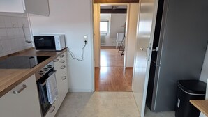 A kitchen with white cabinets, a wooden countertop, a stove, and a refrigerator.