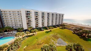 Ein mehrstöckiges Hotel mit Balkonen, einem Swimmingpool und Blick auf den Strand.