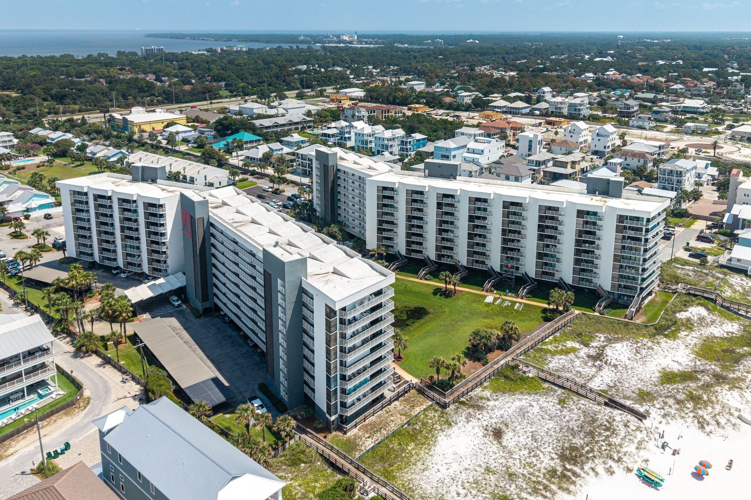 A high-rise hotel with multiple balconies, a central courtyard, and a beach view.